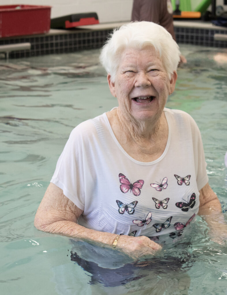 elderly lady in private clinical hydrotherapy pool smiling and enjoying physiotherapy